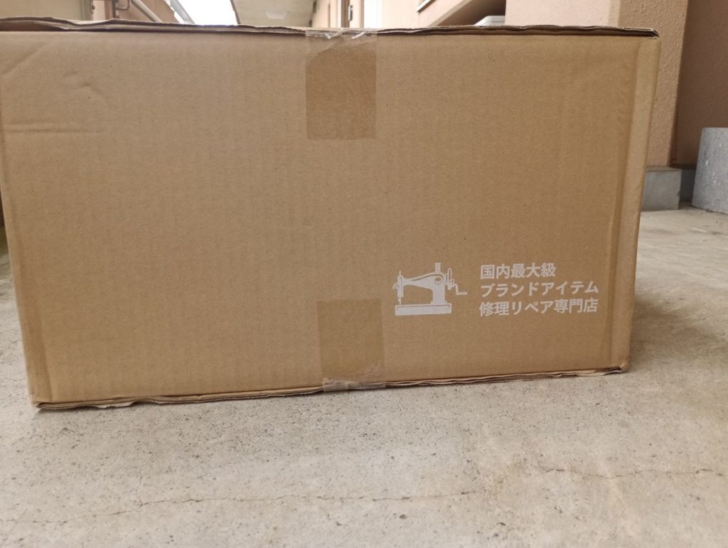プロショップひらいしやから届いたダンボールを左側面から撮った写真。国内最大級ブランドアイテム修理リペア専門店と書いてある。