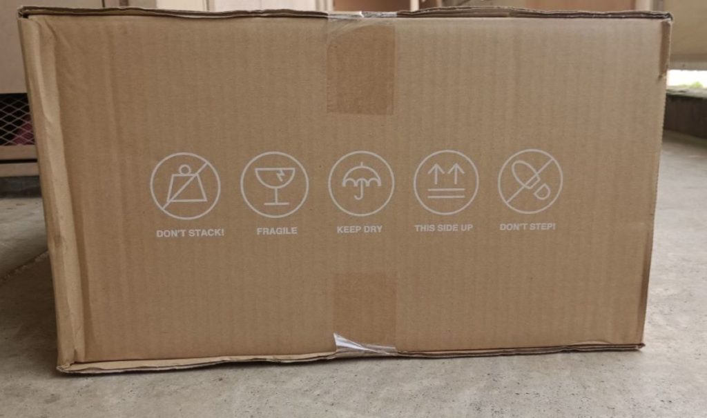 プロショップひらいしやから届いたダンボールを右側面から撮った写真。英語で積み上げ厳禁、もろい、踏まないなど注意書きが書かれてある。
